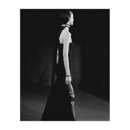 Model in a black strapless evening gown and choker necklace walking on a runway in Paris photographed by Paul Phung.
