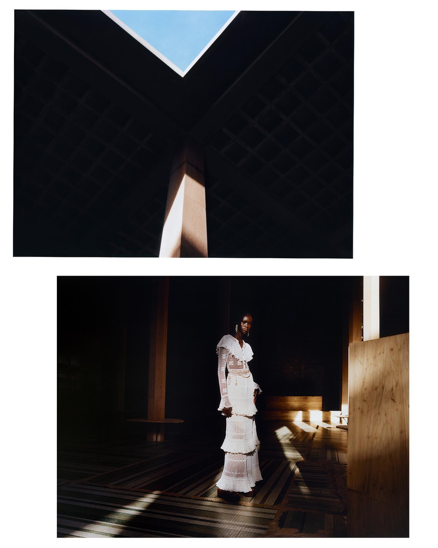 Elegant woman in a tiered white dress stands inside a minimalist interior with geometric light patterns and a skylight above.