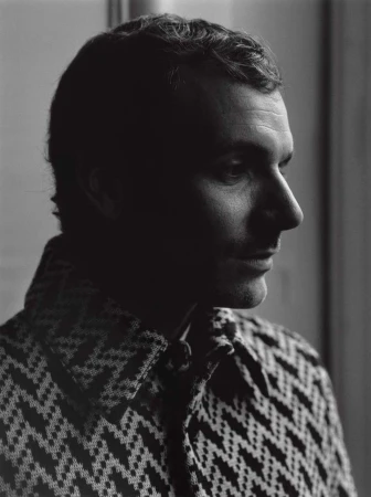 Monochrome portrait of a man in a patterned houndstooth jacket shot in profile by Paul Schmidt in Paris.