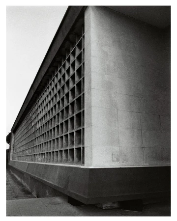 Monochrome architectural photograph of a large concrete building with a gridded louvered facade in Paris.