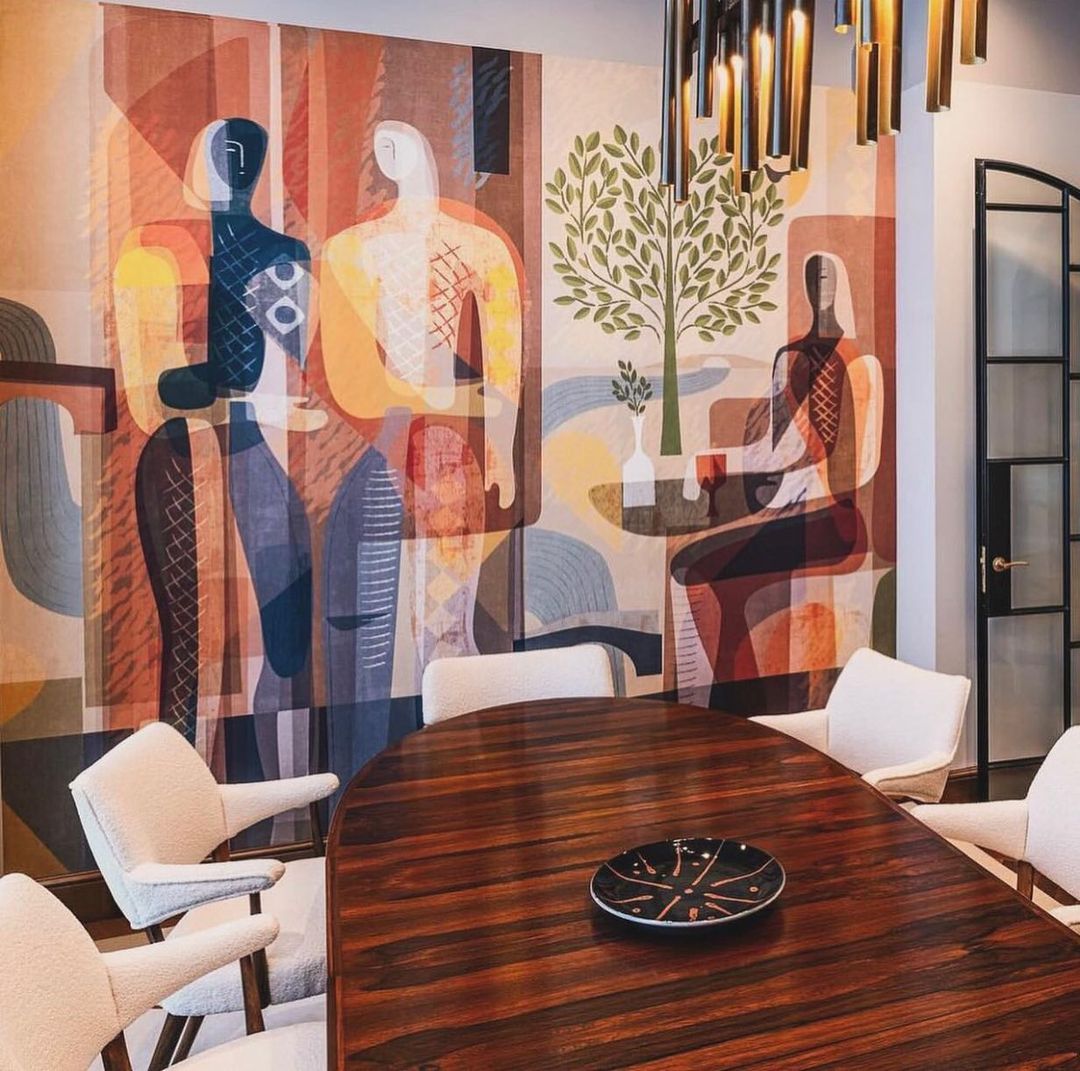 Interior view of a dining room with an abstract mural on the wall featuring human figures, a table, and white upholstered chairs.