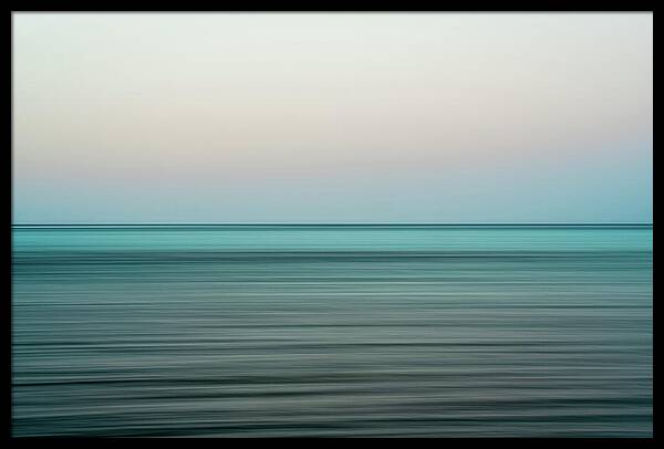 Minimalist landscape photograph capturing a long exposure of turquoise ocean water beneath a soft pale sky