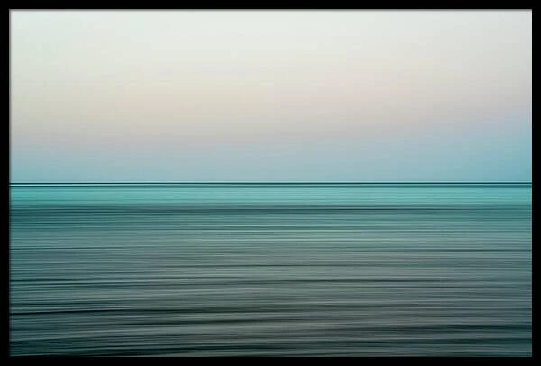 Minimalist landscape photograph capturing a long exposure of turquoise ocean water beneath a soft pale sky