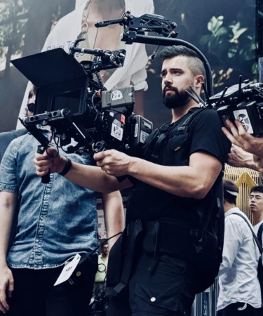 Cinematographer operating a heavy professional movie camera rig on location in New York City with a rig harness and matte box