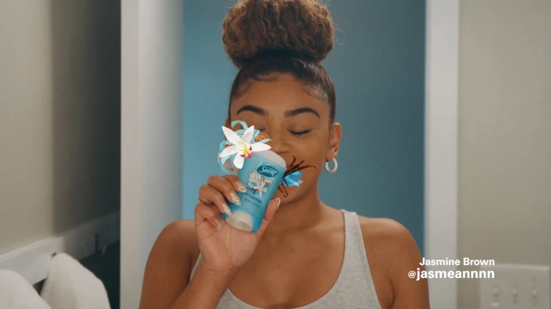 Young woman holding a deodorant stick to her nose with floral and vanilla illustrations