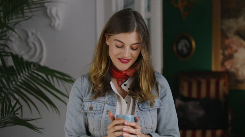 Woman in denim jacket holding a ceramic mug with a red bandana around her neck