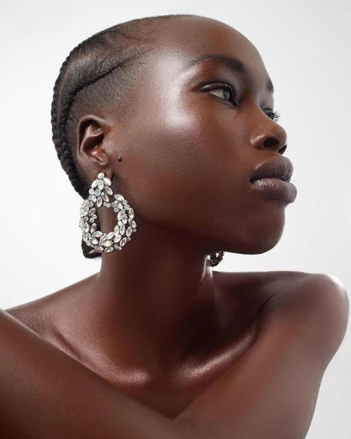 Headshot of a Black woman in a sleeveless top, with braided hair and dangling crystal earrings against a plain white background.
