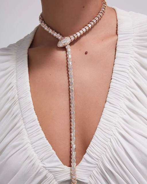 Woman wearing diamond snake necklace. Close-up shot of the snake-shaped jewelry. Diamond details, luxury aesthetic, light and airy setting.