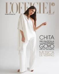 Magazine cover featuring a woman wearing an asymmetrical white top and matching trousers against a white background.