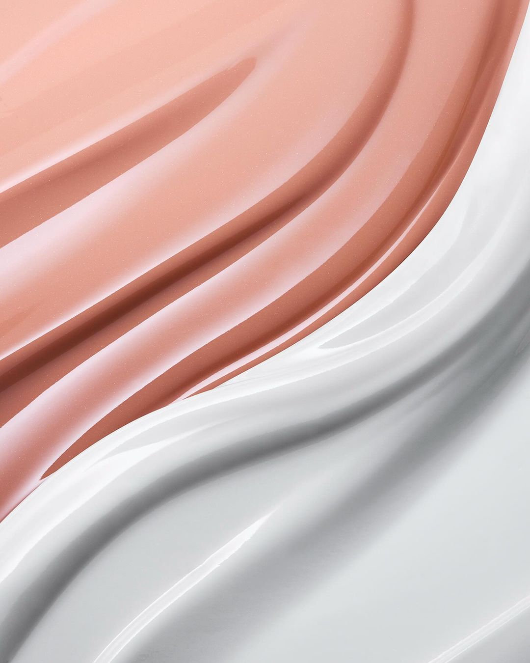 Close-up shot of swirled white and light pink cream, showcasing glossy textures and subtle color variations in a dynamic, abstract design.