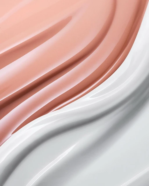 Close-up shot of swirled white and light pink cream, showcasing glossy textures and subtle color variations in a dynamic, abstract design.