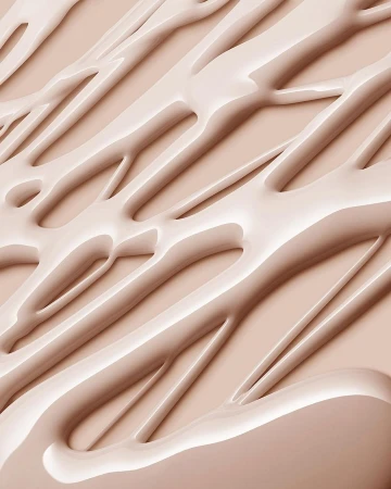 Abstract close-up of beige-toned cosmetic cream or liquid foundation with smooth, glossy texture and diagonal linear patterns.
