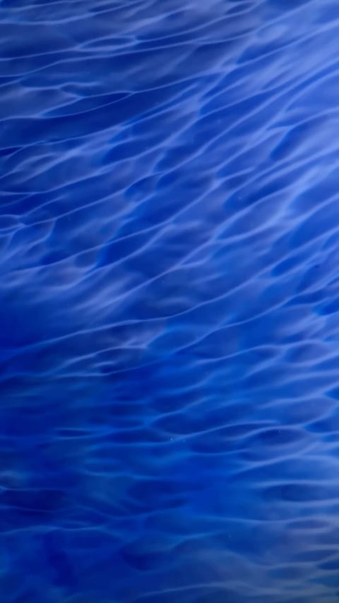 Abstract image of rippling deep blue water creating textured waves in a fluid design, reminiscent of a serene ocean surface.