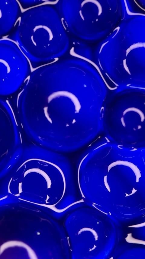 Close-up of translucent blue spheres with glossy surfaces and white curved highlights by Pauline Choffé