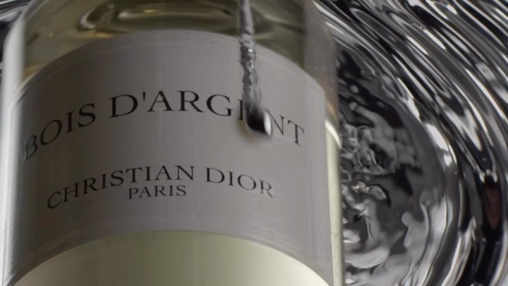 Crystal Dior perfume bottle in high-end beauty shot featuring liquid ripples and brand label, capturing luxury and elegance.