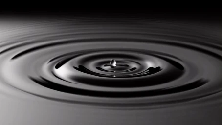 Monochrome CGI rendering of concentric water ripples expanding from a central droplet on a dark surface.