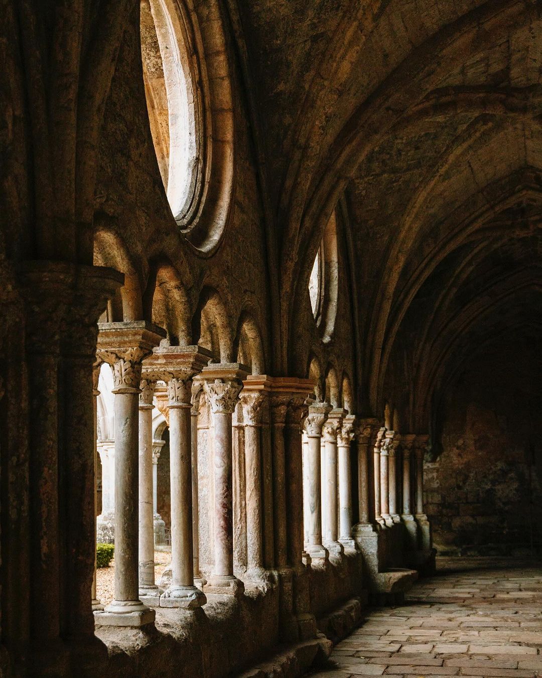 Stone columns and arched ceiling in a historic building, featuring architectural details and soft, diffused lighting, creating an elegant atmosphere.