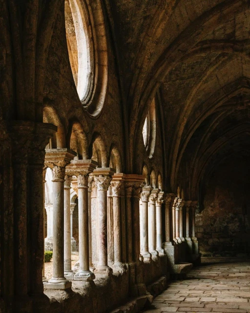 Stone columns and arched ceiling in a historic building, featuring architectural details and soft, diffused lighting, creating an elegant atmosphere.