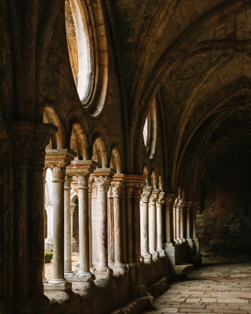 Stone columns and arched ceiling in a historic building, featuring architectural details and soft, diffused lighting, creating an elegant atmosphere.
