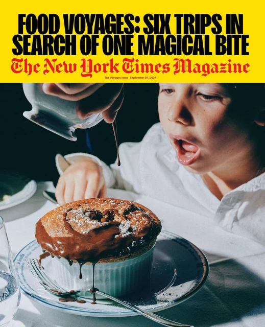 Child looking at chocolate sauce being poured over a souffle on a plate. The image is a magazine cover on a yellow background.