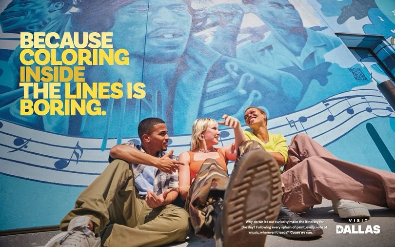 Three people sit in front of a mural, smiling. The mural features musical notes and the text: "Because coloring inside the lines is boring."