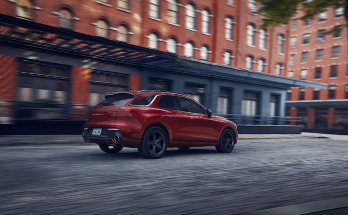 Red luxury SUV driving on a city street with blurred red brick buildings in the background
