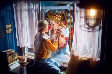 Two women kneeling and pressing hands against a glass window, shot by Per Kasch in Hamburg