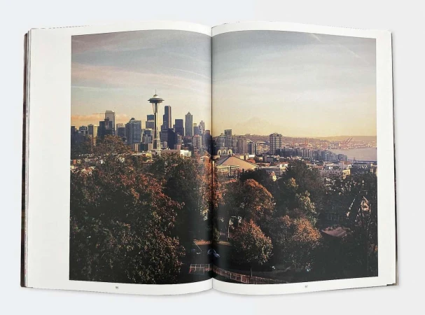 Seattle skyline from a distance, featuring the Space Needle and skyscrapers under a bright sky, as seen in a photography book.