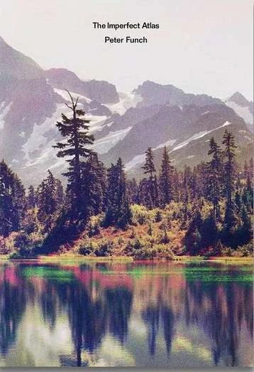 Scenic view of a mountain range with snow and a forest reflecting in a lake on the cover of 'The Imperfect Atlas' by Peter Funsch.