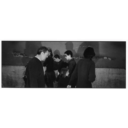 Monochrome panoramic street photograph capturing a group of people walking past a wall with cast shadows by Peter Funch