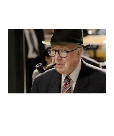 Elderly man with hat and glasses smoking a pipe, wearing a dark suit and patterned tie, against a blurred background.