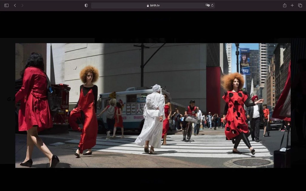 Fashion editorial photo of diverse women in red and white dresses walking on a city street crosswalk with city buildings and a food truck.