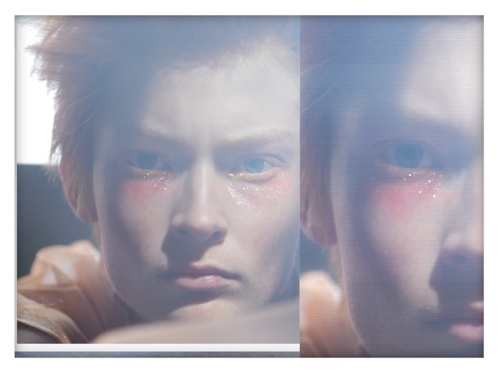 Close up of a person with red hair and a neutral facial expression, shot through a translucent film, possibly for a beauty campaign.