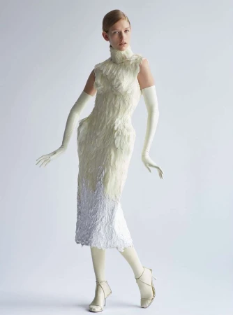 Fashion model in studio wearing a white feather dress, gloves, and high heels. Full-length shot on white background, high fashion.