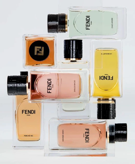 Collection of Fendi perfume bottles arranged on a white surface, showcasing various colors and bottle designs. Studio shot.