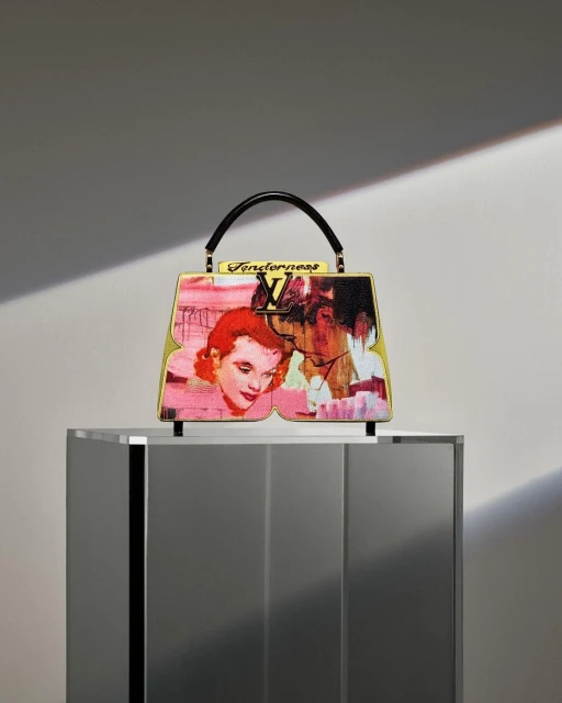 Artistically decorated Louis Vuitton handbag, featuring a vintage couple design and 'Tenderness' script, placed on a gray column.