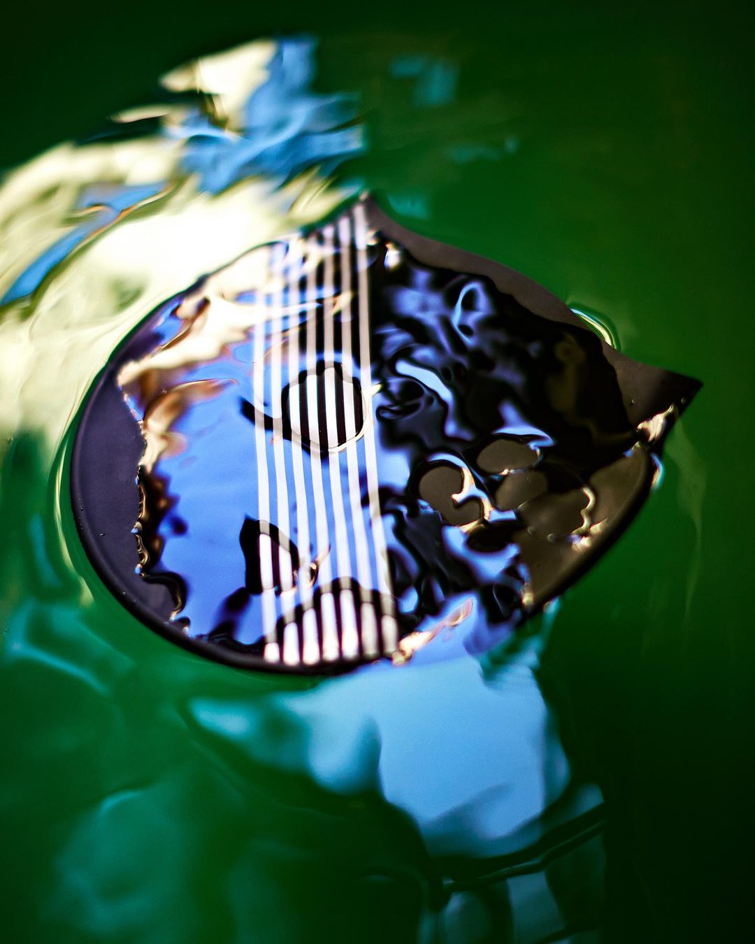 Abstract composition of an object under green tinted water with rippled surface, creating distorted reflections and refractions of light.