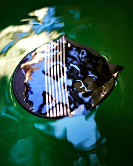 Abstract composition of an object under green tinted water with rippled surface, creating distorted reflections and refractions of light.