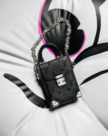 Black Louis Vuitton box bag with a silver chain strap and silver hardware, resting on a white surface with black and pink accents.