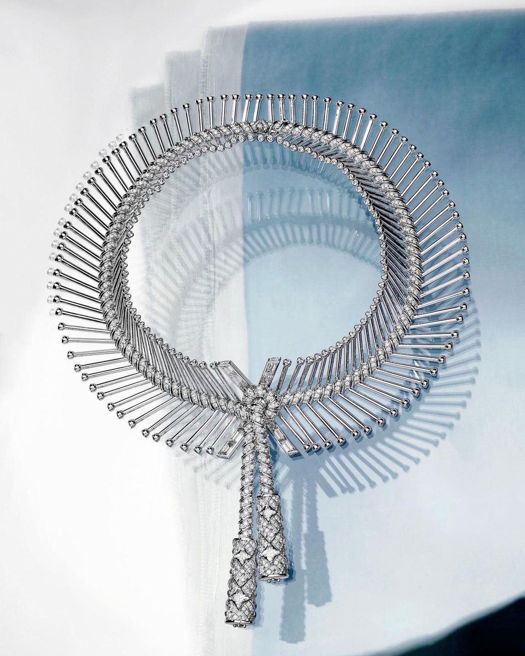 Elegant silver necklace featuring intricate diamond embellishments and a unique design, displayed against a soft, gradient background.