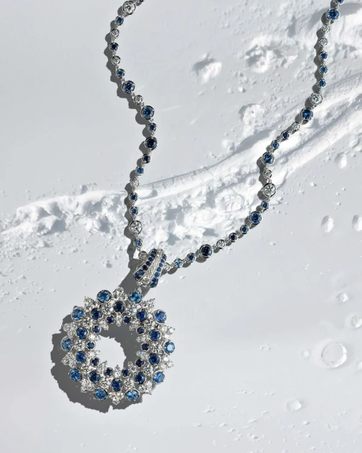 Elegant necklace with blue and white gemstones displayed on a textured white surface in a high-angle product shot for jewelry design.