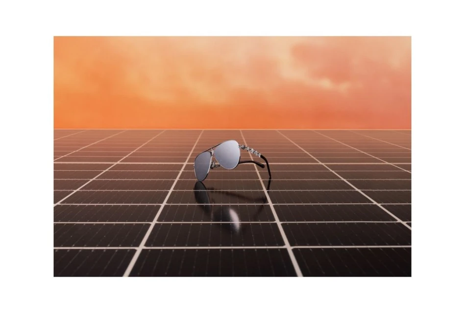 Aviator sunglasses on a solar panel against an orange sky. The reflective lenses mirror the landscape, creating a modern still life.