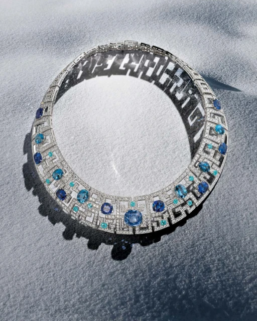 Overhead studio shot of a diamond and sapphire necklace, displaying intricate geometric details and a bright, luxurious aesthetic.