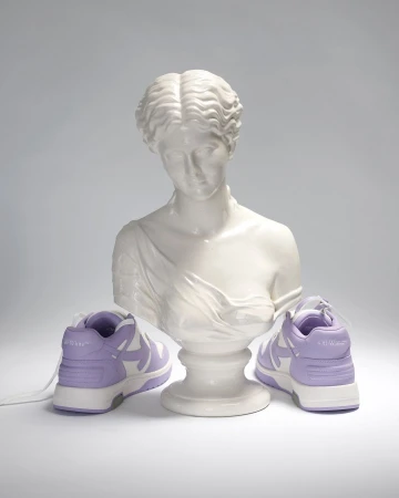 Still life shot of lavender and white sneakers flanking a Greco-Roman style bust on a neutral background. Fashion footwear.