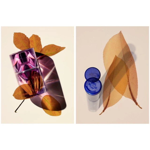 Purple perfume bottle displayed with orange leaves, adjacent to a transparent container with a blue lid and leaves.