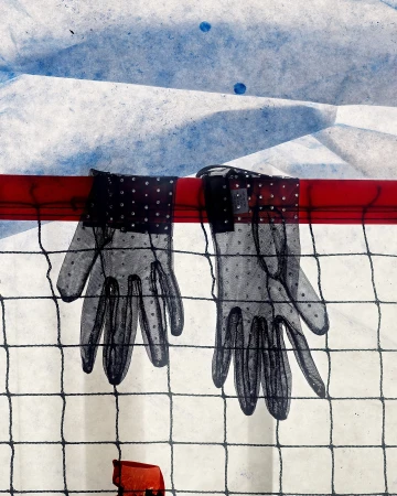Pair of sheer black gloves with polka dots hanging on a red bar against a textured white and blue backdrop and black mesh screen.