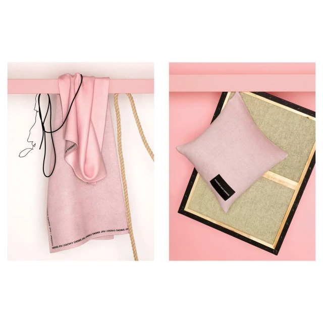 Stylized studio shot of a pink towel and a pillow on a pink shelf with pink background, paired with ropes and a framed artwork.