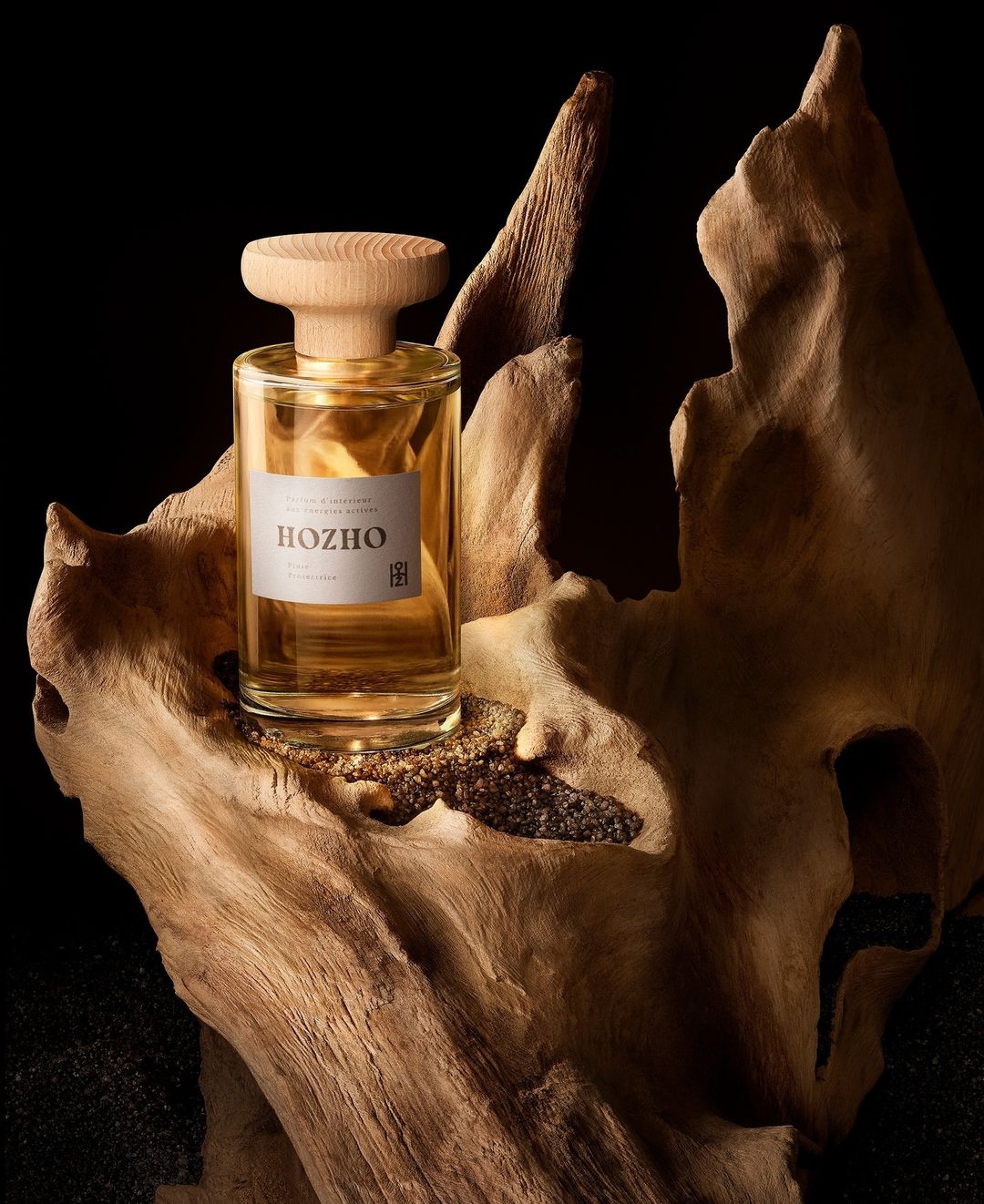 Elegant perfume bottle with wooden cap on textured wood, set against a dark backdrop creating a luxurious and natural fragrance aesthetic.