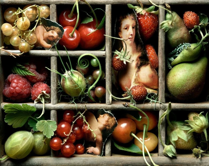 Still life arrangement of fresh fruits, including cherries, strawberries, pears, raspberries, and grapes, displayed in a partitioned wooden box.