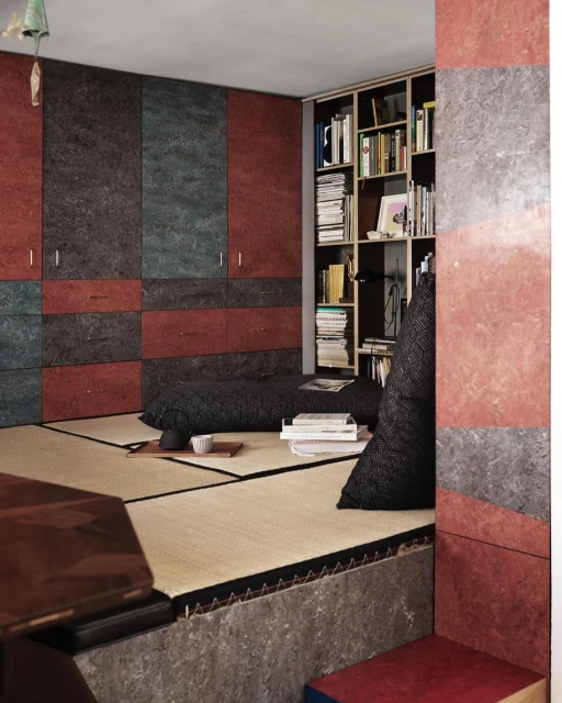 Tatami mat platform in a modern Japanese-style room with a bookcase, textured walls, dark cushions, and minimal teaware.